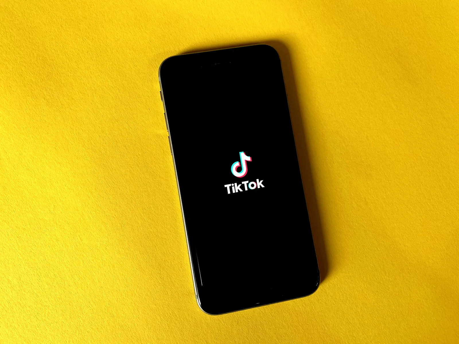 Teléfono con el logotipo de TikTok sobre un fondo amarillo